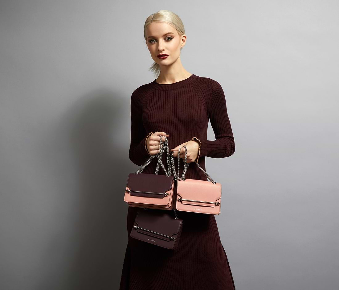 A woman in a brown dress holding two purses