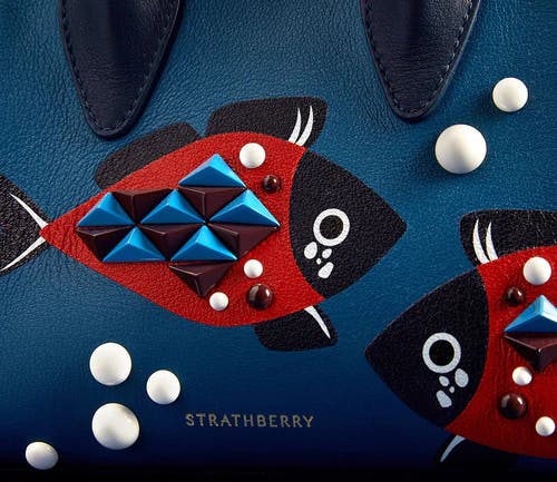 A blue purse with a red fish design on it