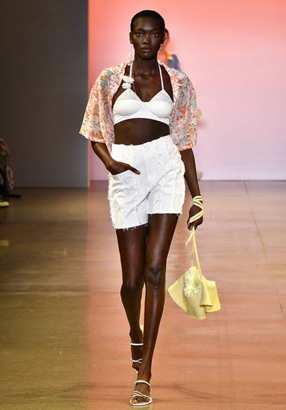 A woman walking down a runway with a yellow purse