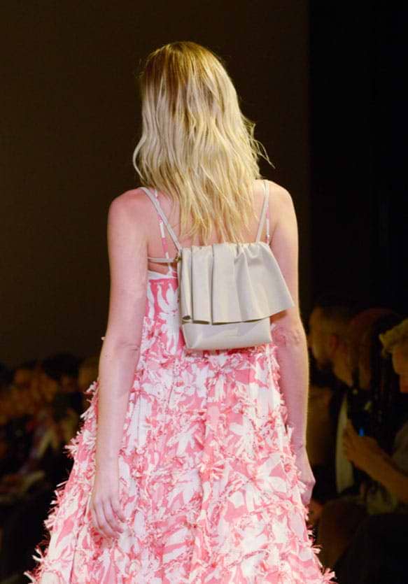 A woman walking down a runway in a pink dress