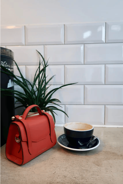 A red purse sitting next to a cup of coffee