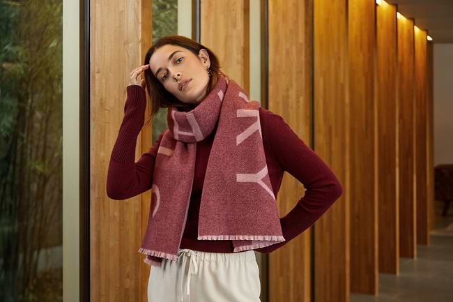 A woman wearing a red scarf standing in front of a wooden wall