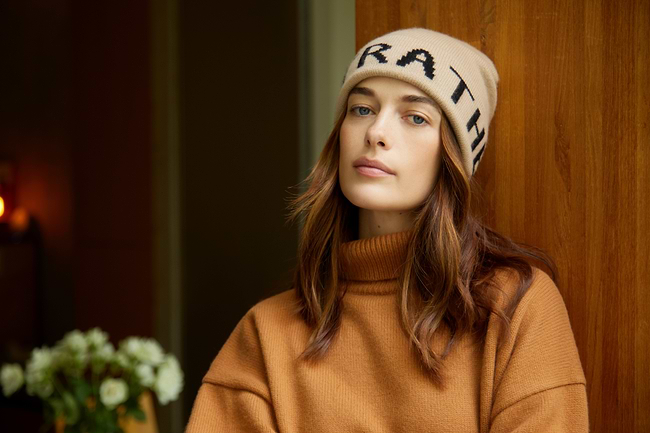 A woman wearing a brown sweater and a hat