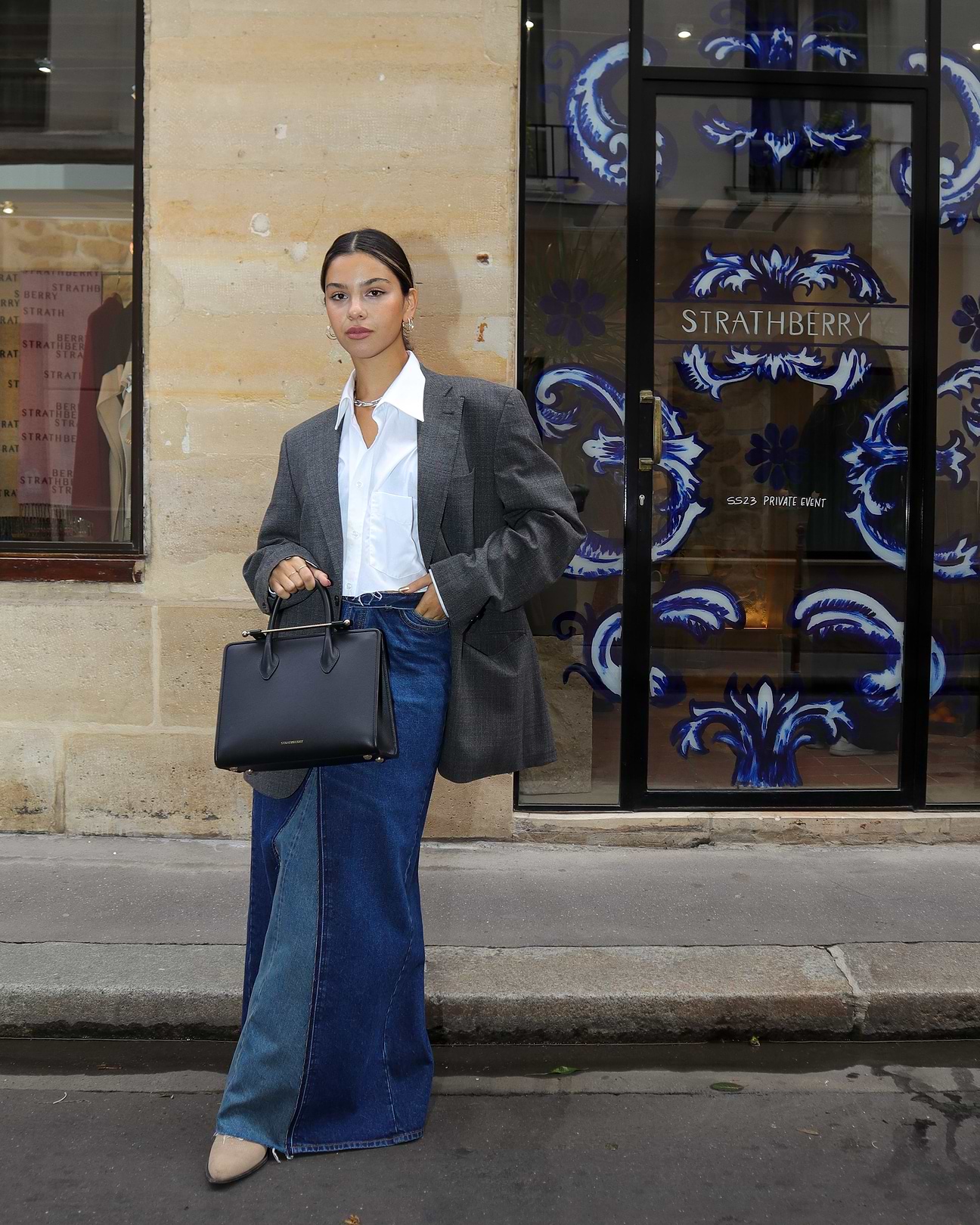 A woman standing on the side of a street holding a handbag