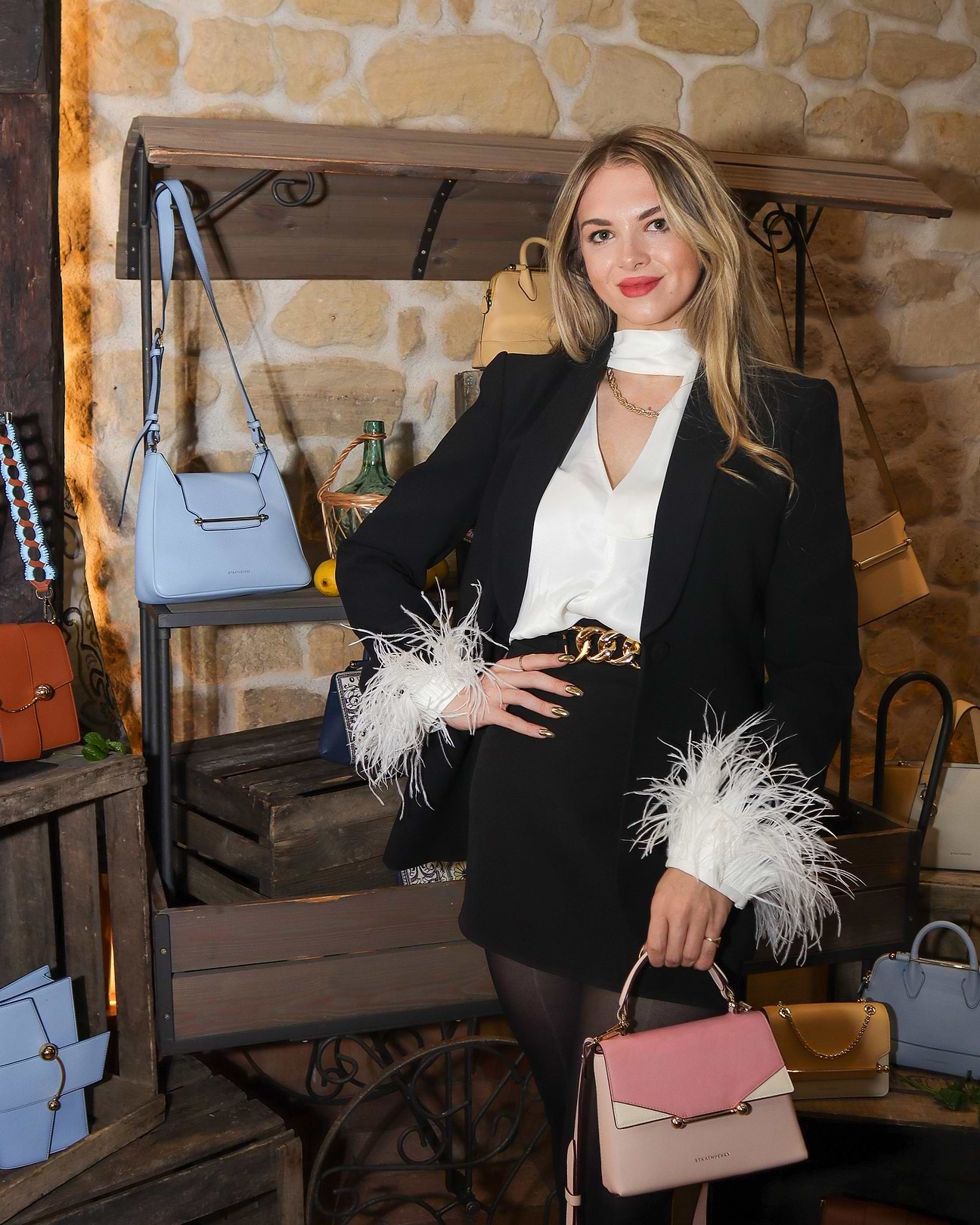 A woman in a black jacket and white shirt holding a pink purse