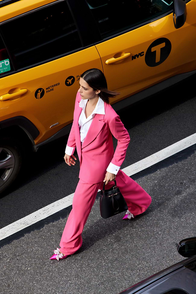 A woman in a pink suit crossing the street