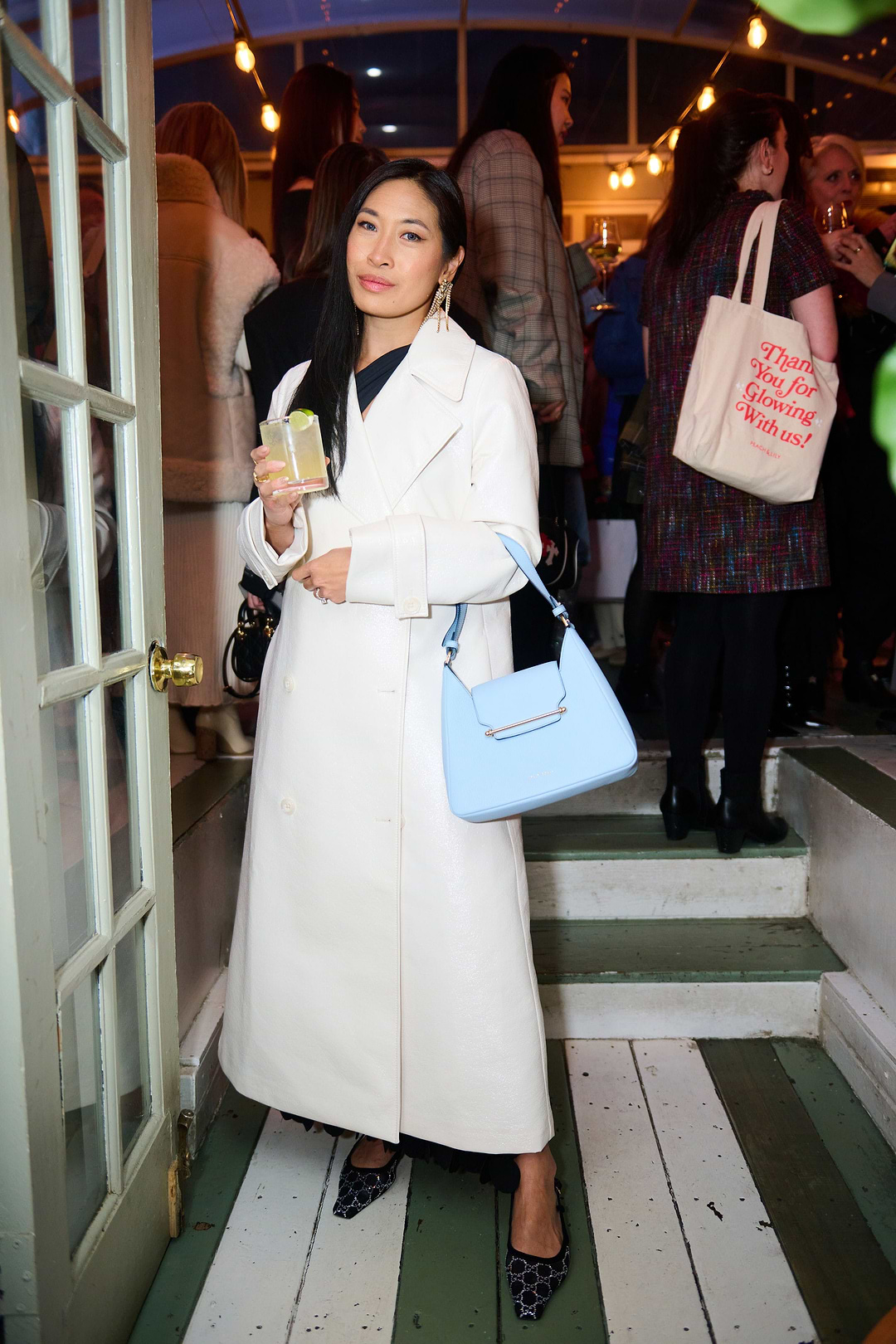 A woman in a white coat holding a blue purse