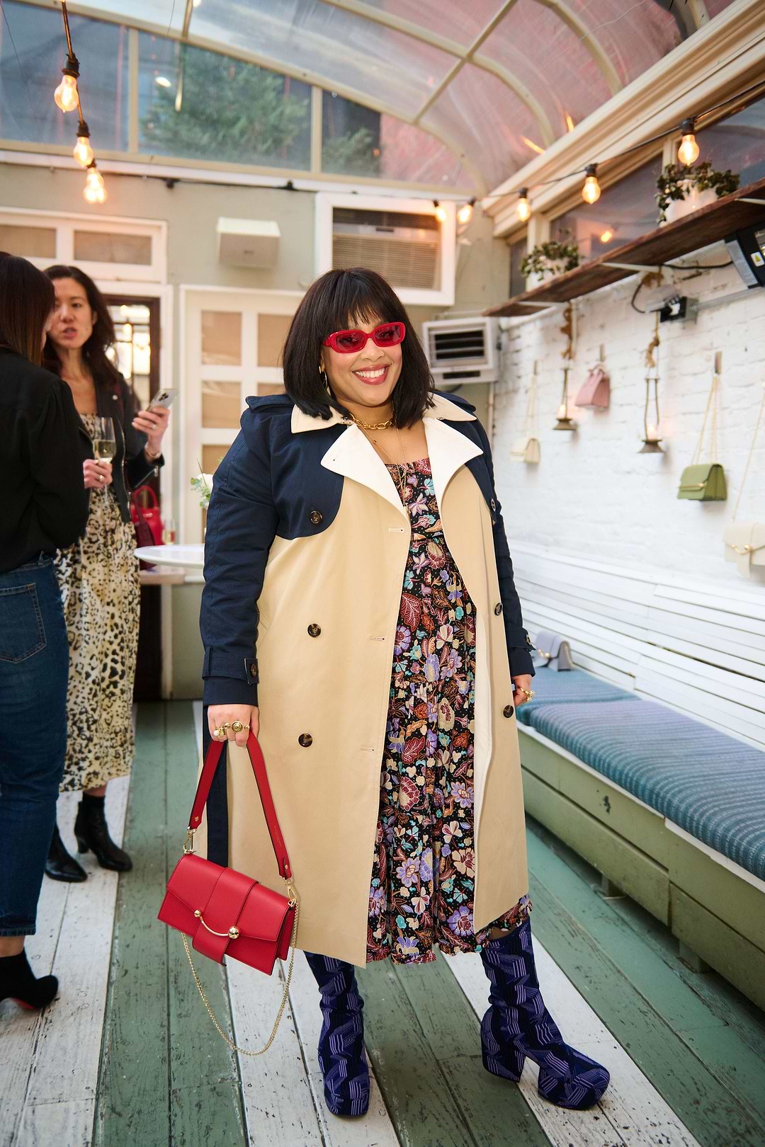 A woman in a trench coat holding a red purse