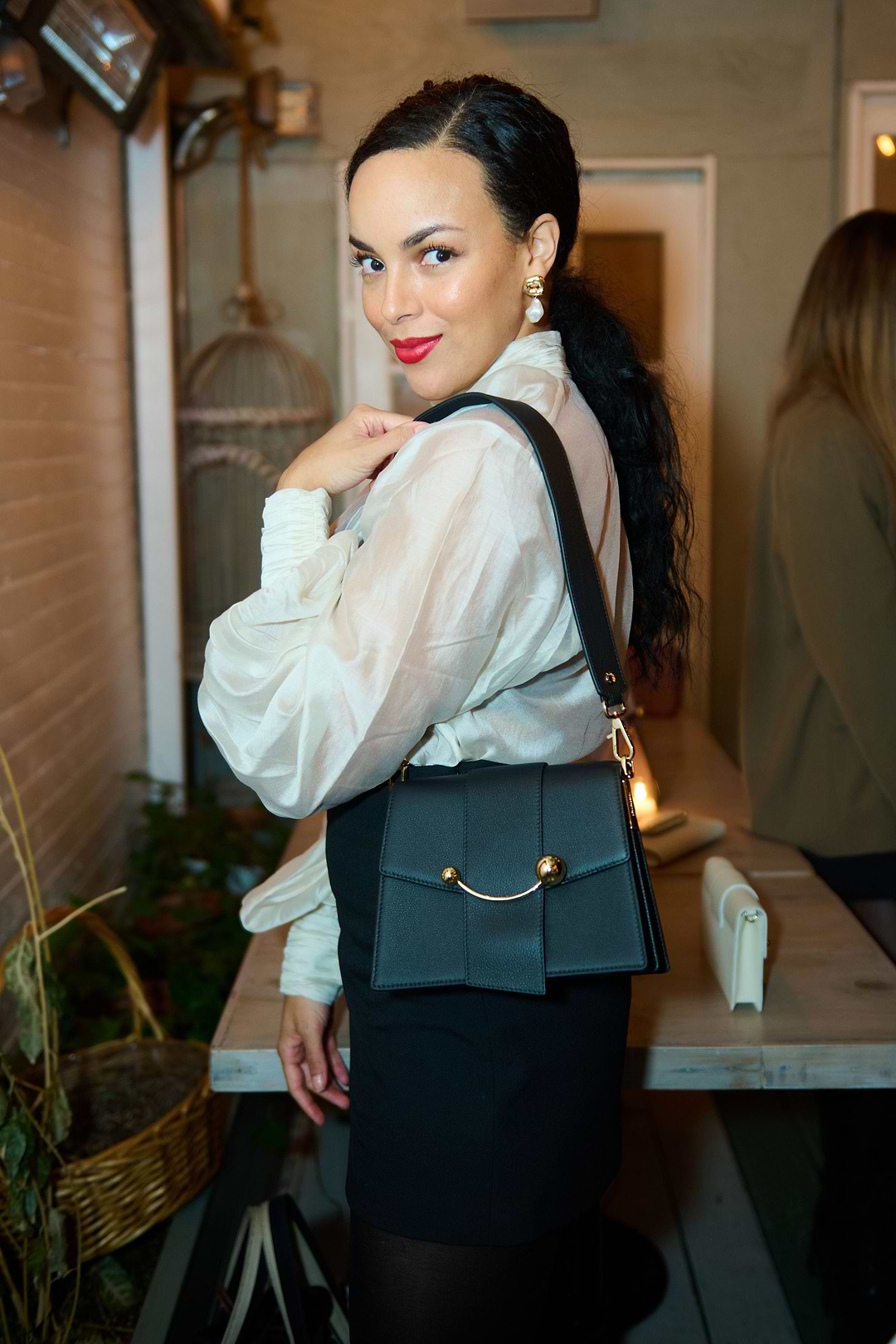 A woman in a white shirt and black skirt holding a black purse