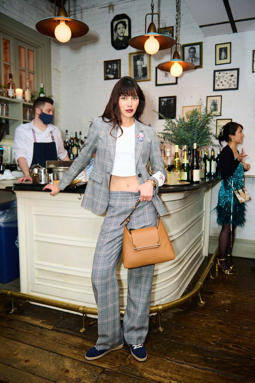 A woman standing in front of a bar holding a purse