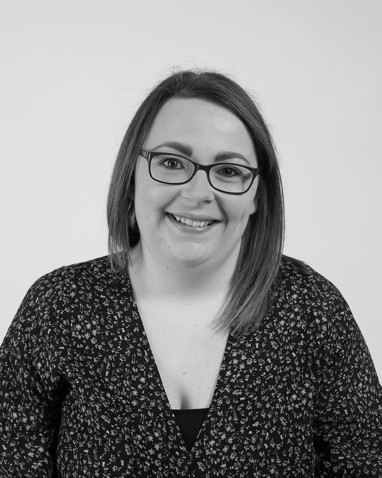 A woman with glasses is smiling for the camera