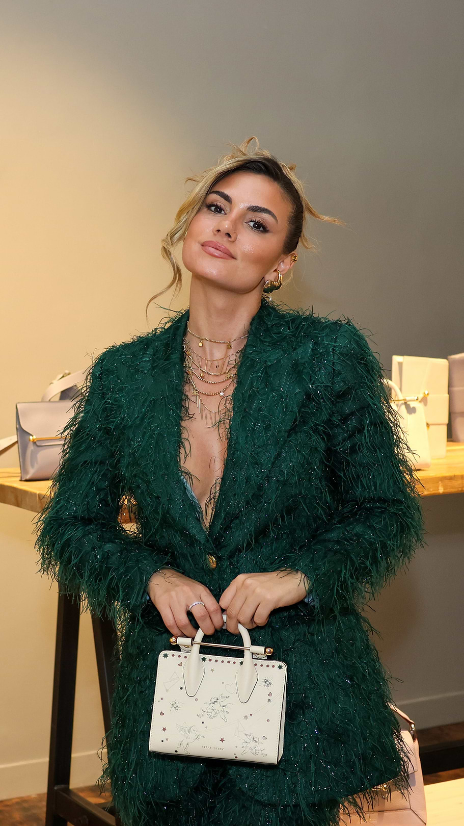 A woman in a green jacket holding a white purse