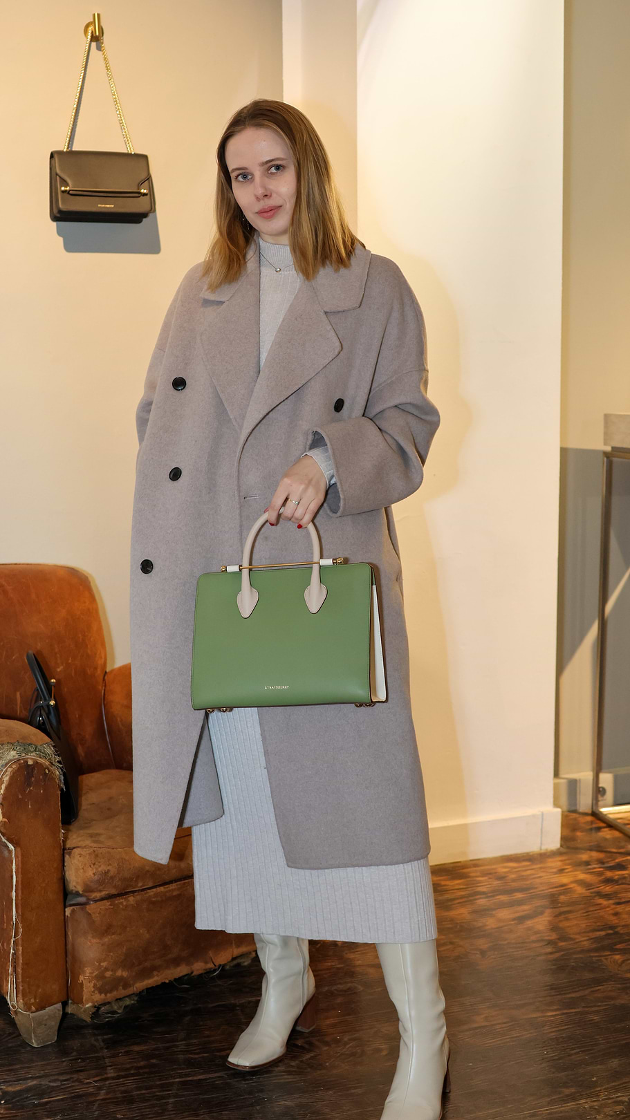 A woman in a gray coat holding a green purse