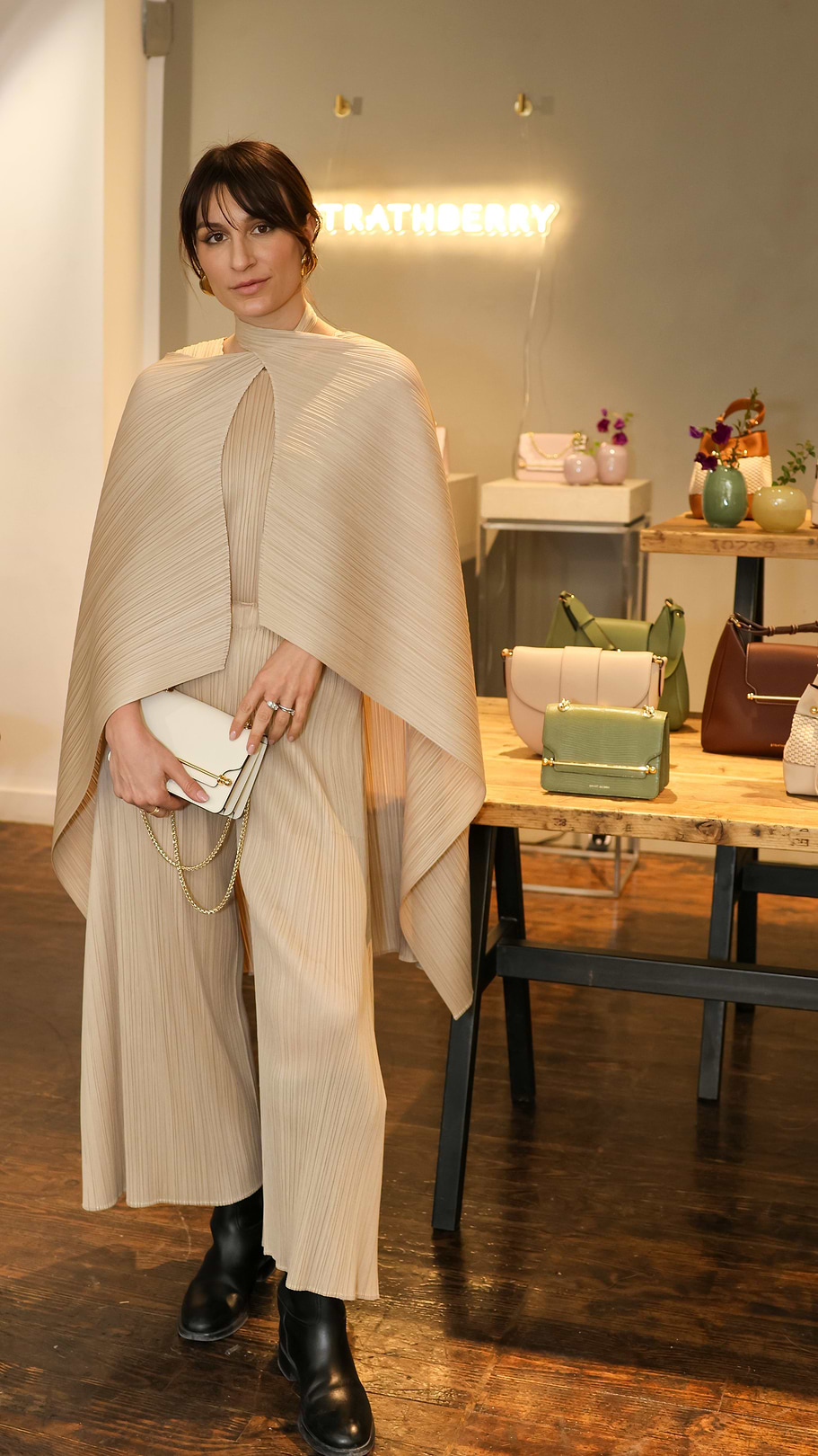 A woman standing in front of a table holding a purse