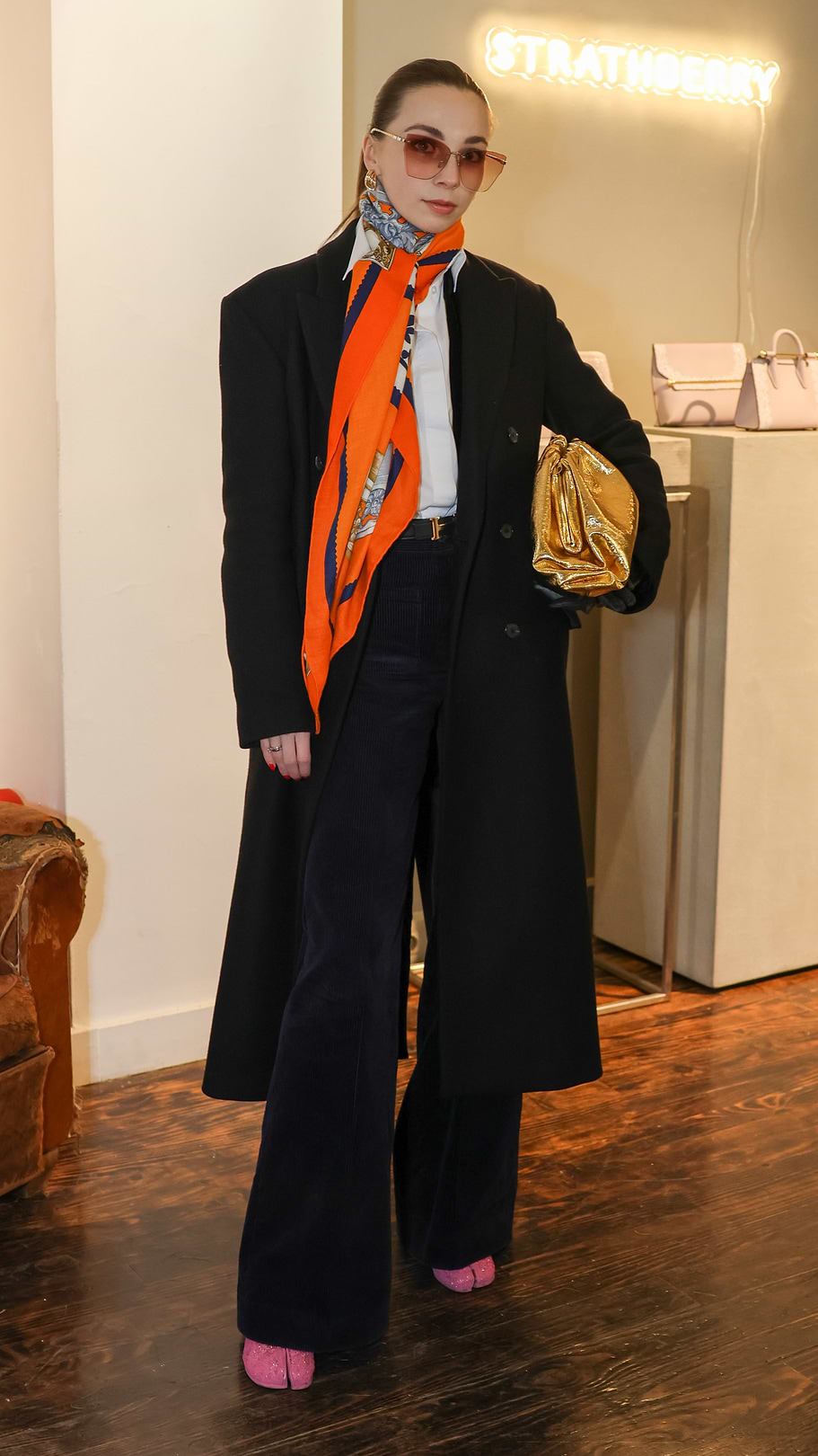 A woman in a black coat and orange scarf