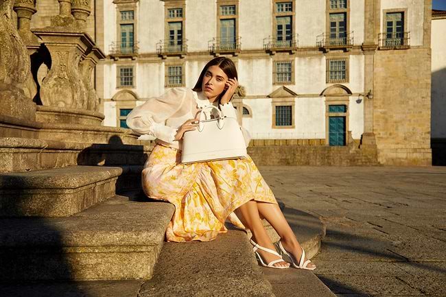 A woman sitting on a ledge with a handbag