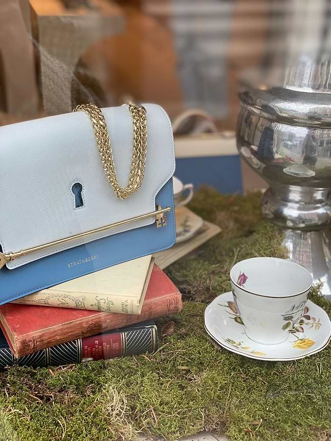 A stack of books and a purse sitting on top of a table