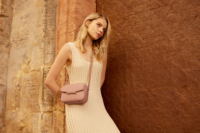 A woman in a white dress leaning against a wall