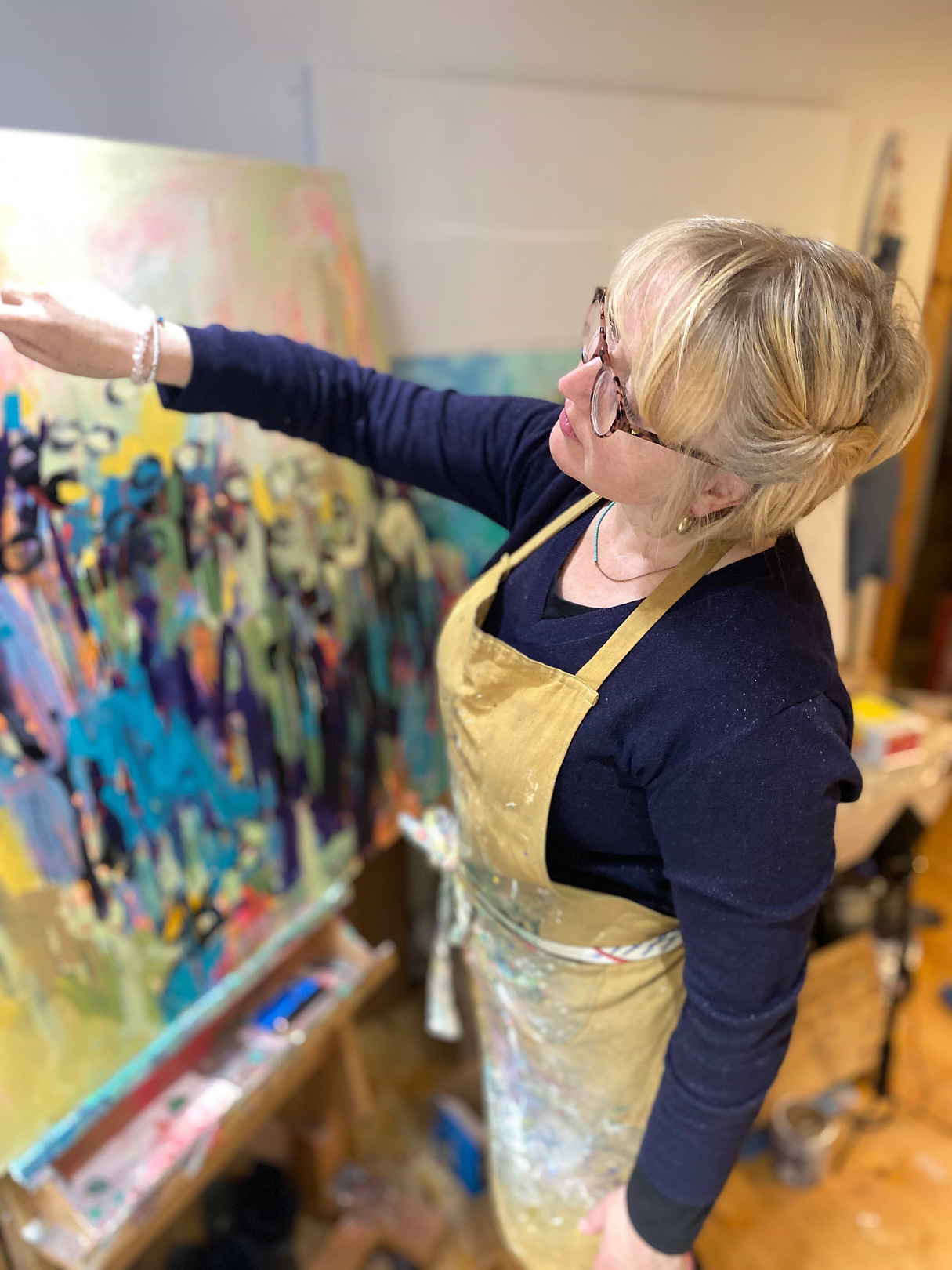 A woman in an apron painting on a canvas
