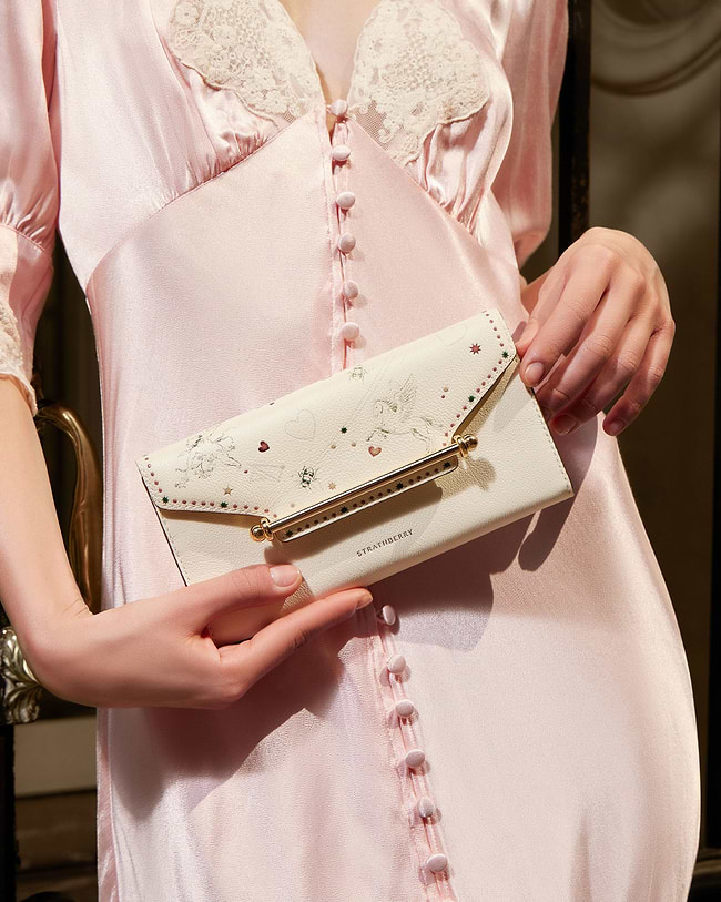 A woman in a pink dress holding a white purse