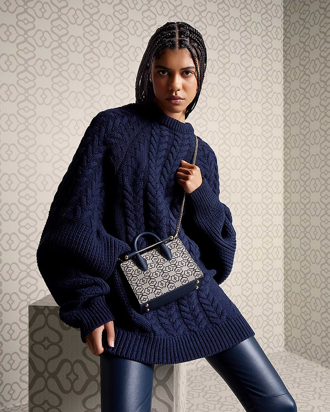 A woman in a blue sweater holding a purse