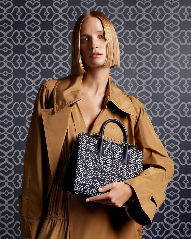 A woman in a trench coat holding a handbag