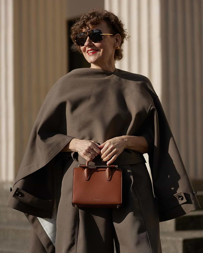 A woman in a brown cape carrying a brown purse