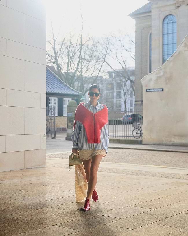 A woman walking down a sidewalk carrying a bag