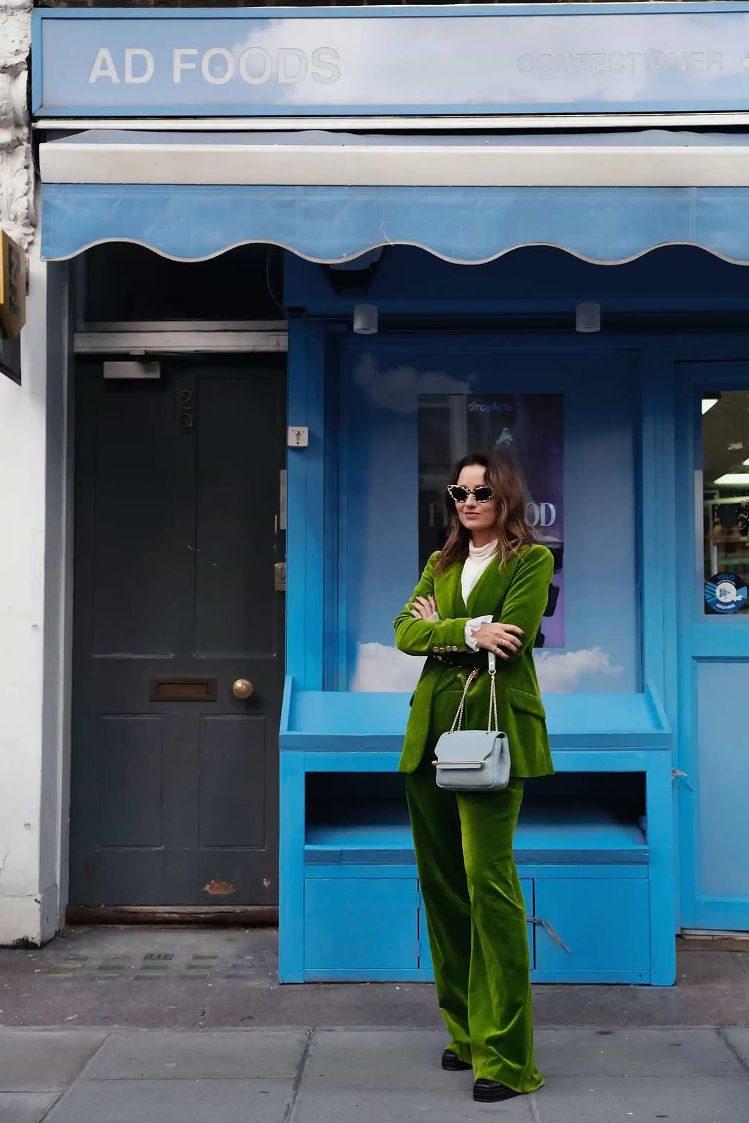 A woman in a green suit standing in front of a store