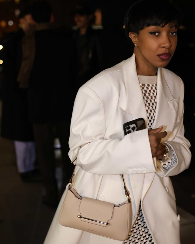 A woman in a white coat carrying a beige purse