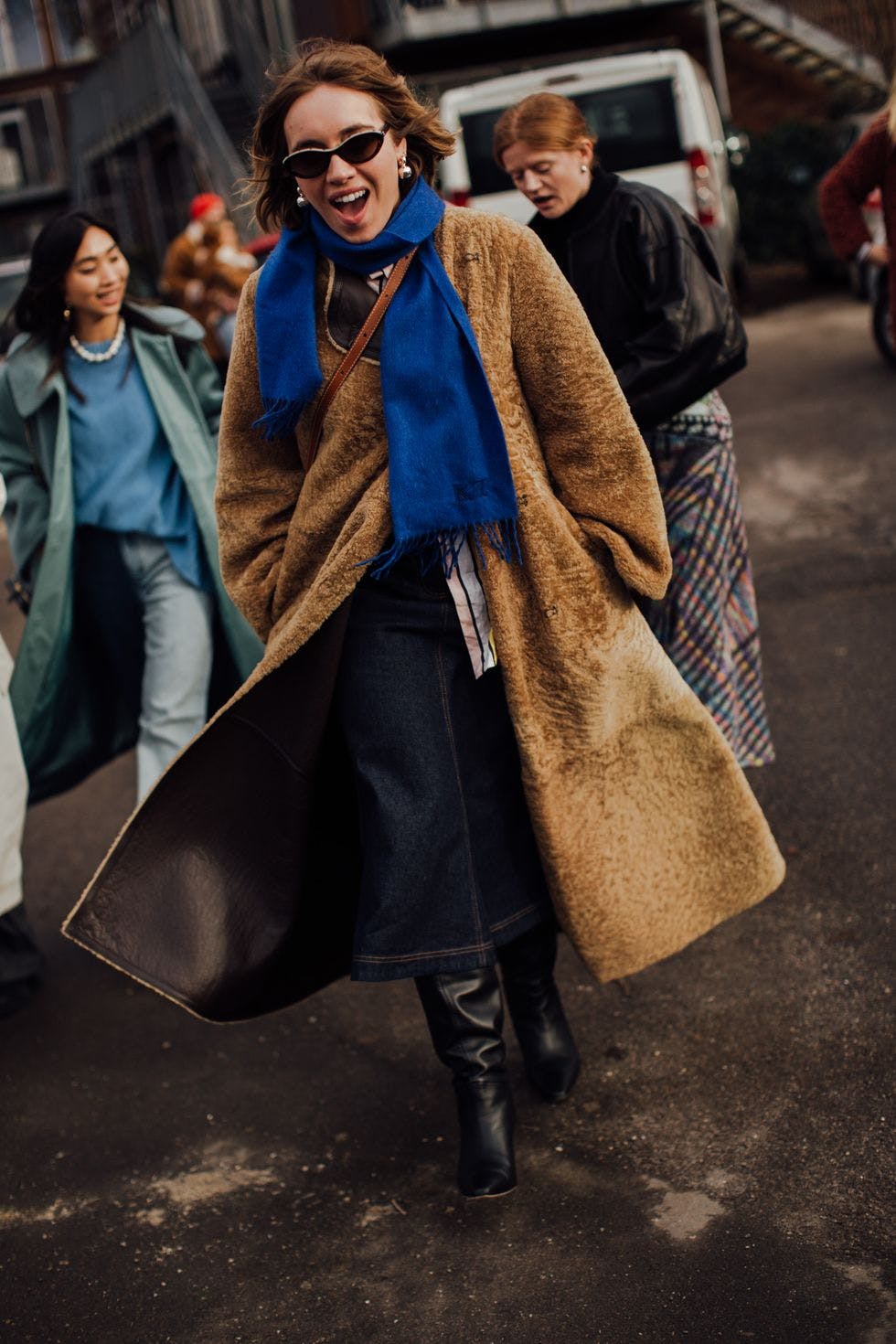 A woman walking down a street with a blue scarf around her neck