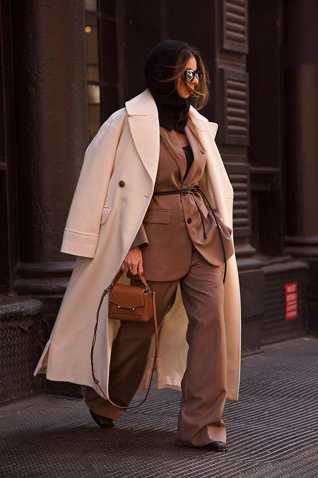 A woman is walking down the street in a trench coat