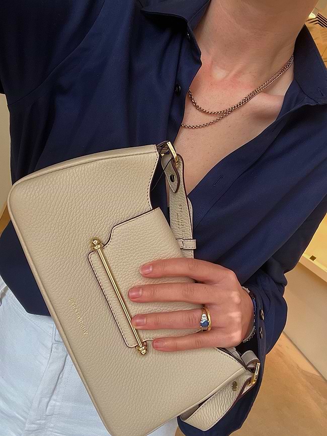A woman wearing a blue shirt holding a white purse