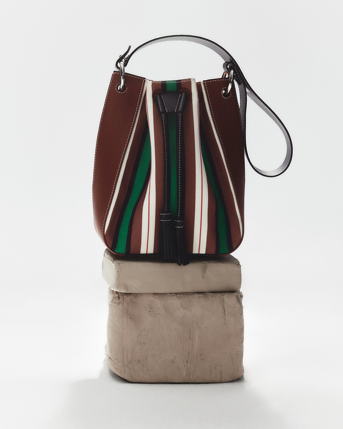 A brown and green purse sitting on top of a block