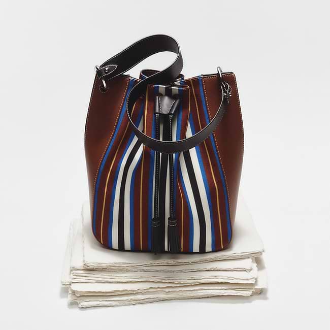 A brown and blue striped purse sitting on top of a stack of white napkins