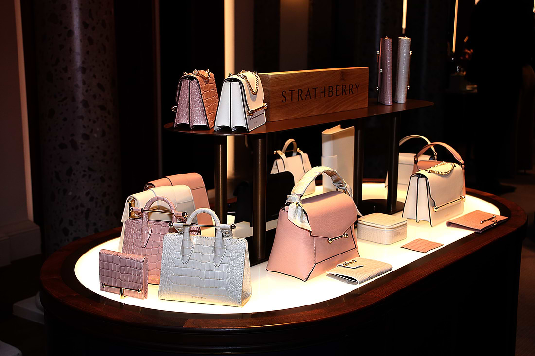 A selection of Strathbery handbags (including two nano tote handbags, a mosaic top handle bag and east/west mini crossbody bag) and small leather accessories (including a melville street wallet and rose street jewellery box) on a light-up display stand. This display was featured at an event held in Scotland in partnership with Hamilton and Inches.