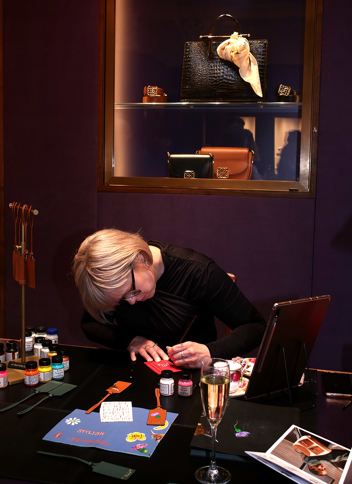 An image captured at our event in Edinburgh, in partnership with Hamilton and Inches. Showing Scottish leather painter, Katy Bell, adding custom Scottish-themed illustrations by paint on our small leather goods.