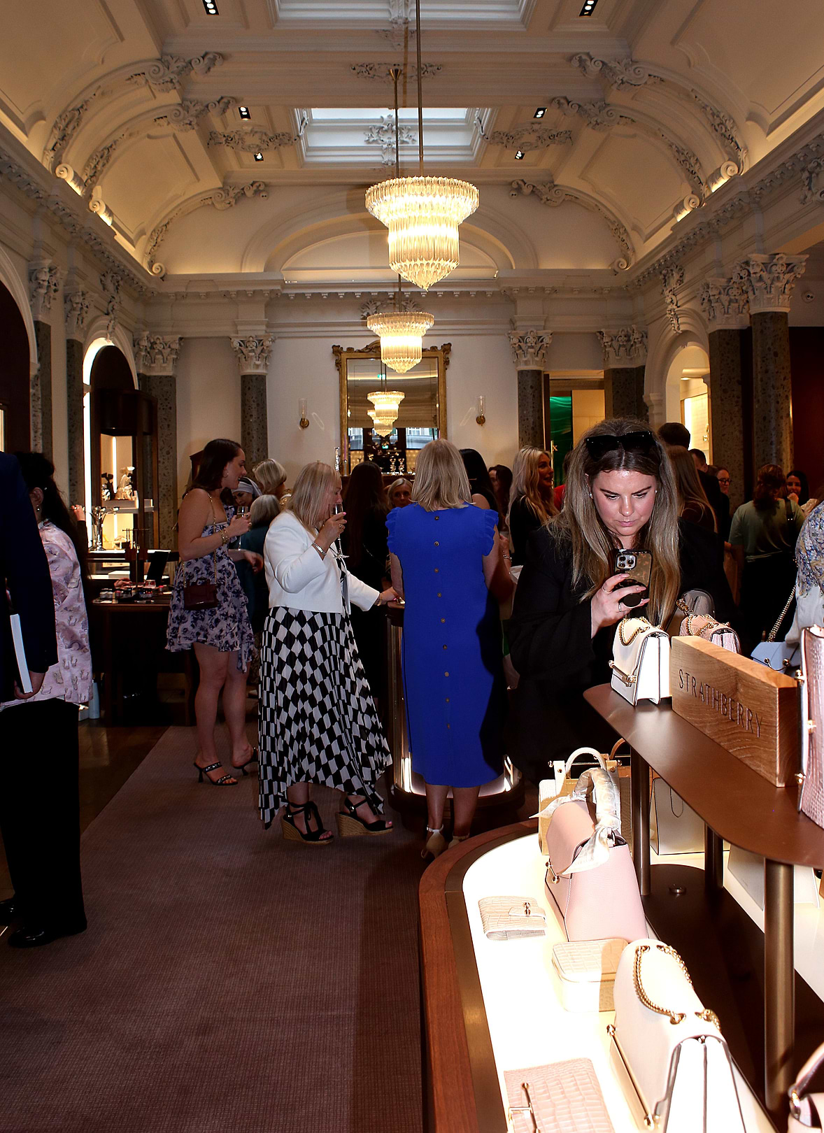 An image captured at our event in Edinburgh in partnership with Hamilton and Inches. A preview of the crowd as they are gathered in the brands grand showroom, where guests can be seen mingling and previewing the goods available from both Strathberry and Hamilton and Inches.