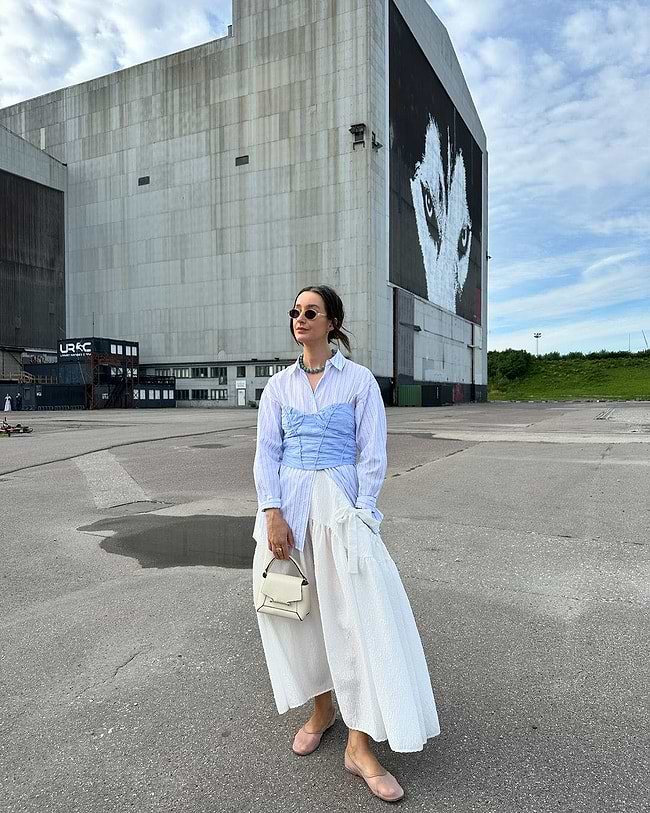 A woman standing in a parking lot with a building in the background