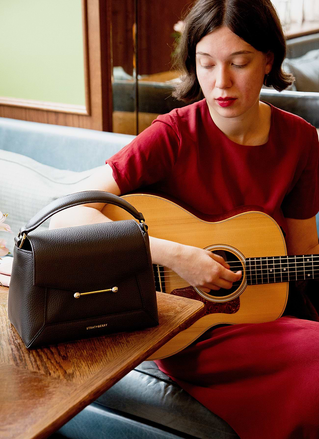 A woman sitting on a couch playing a guitar
