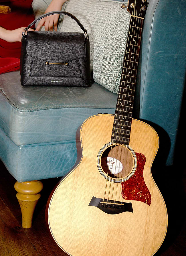 A woman sitting on a couch next to a guitar