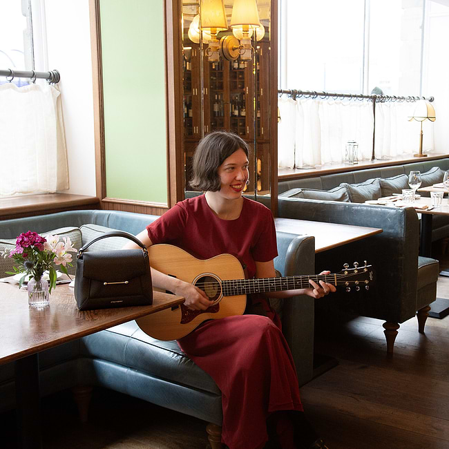 A woman sitting at a table with a guitar