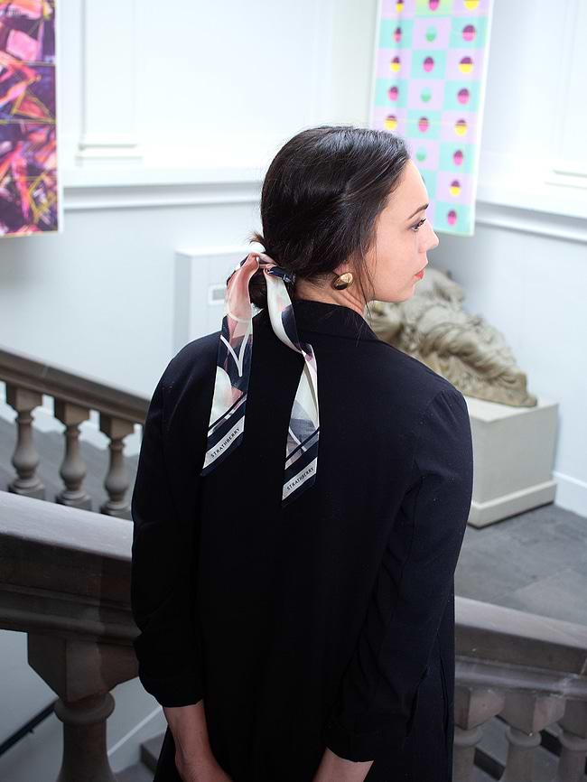 A woman standing on a staircase with a scarf around her neck