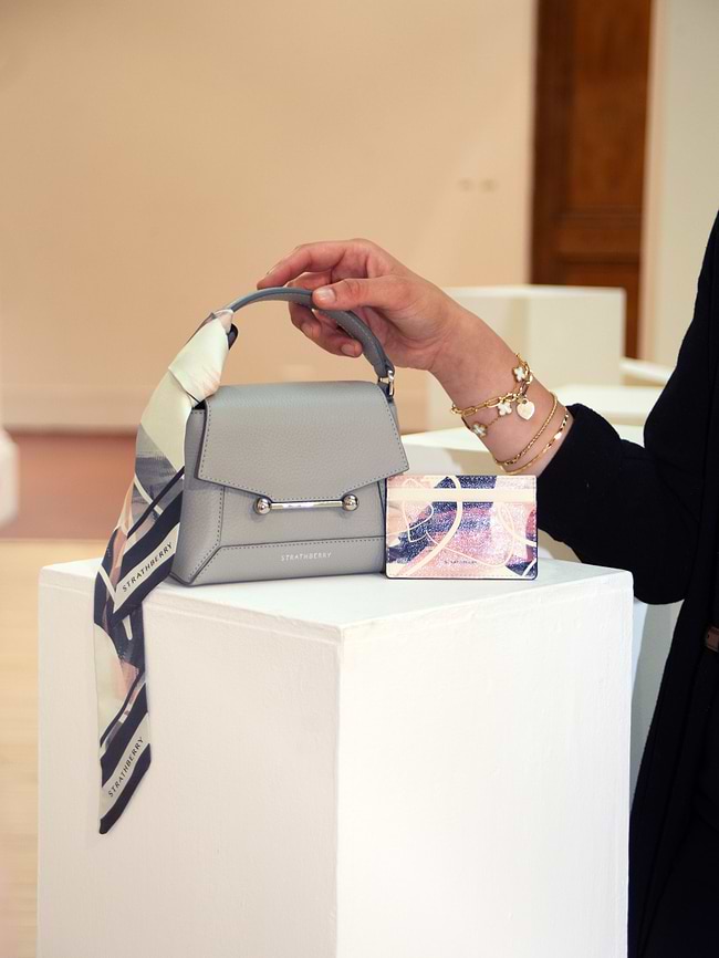 A woman holding onto a gray purse on top of a white box
