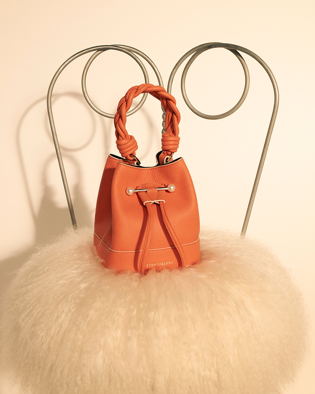 An orange purse sitting on top of a chair