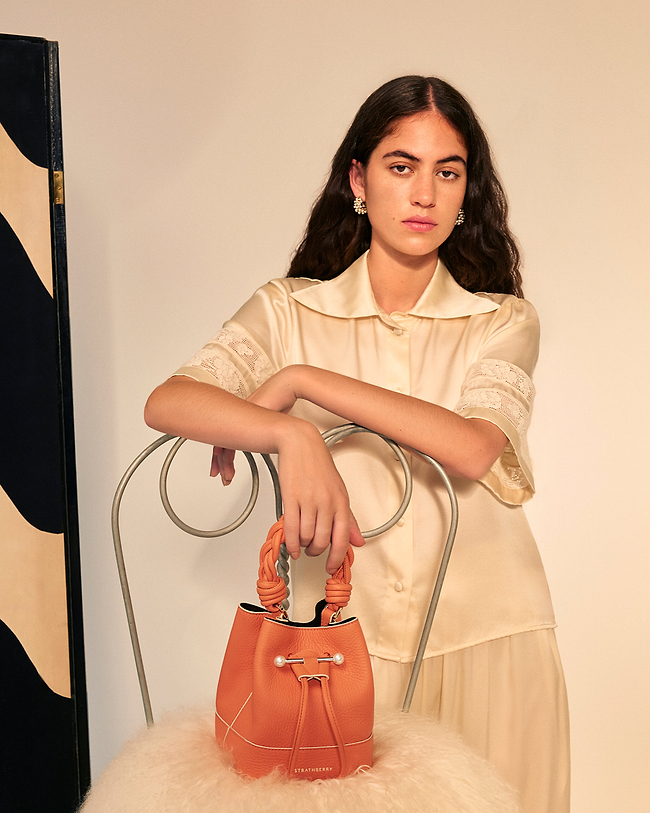 A woman in a white dress holding a brown purse