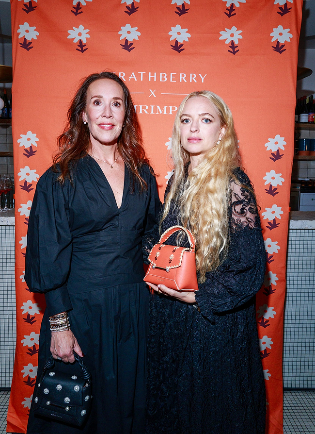 Two women standing next to each other holding purses