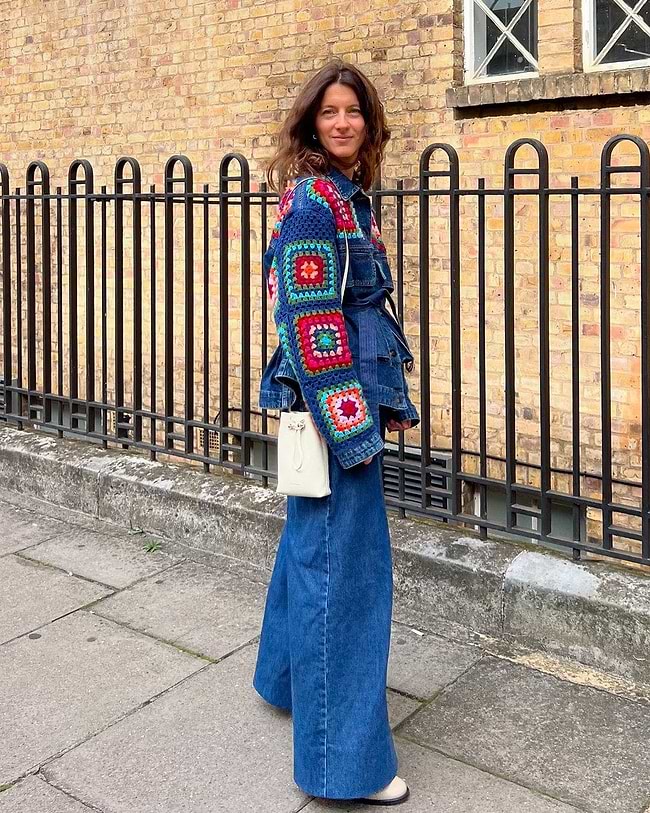 A woman standing on a sidewalk in front of a fence