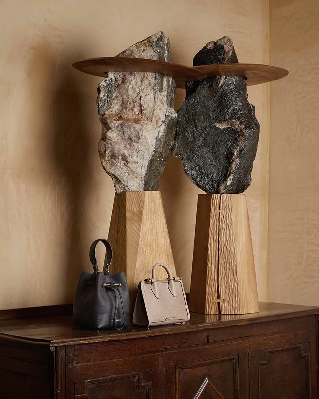 A wooden table topped with two rocks and a purse