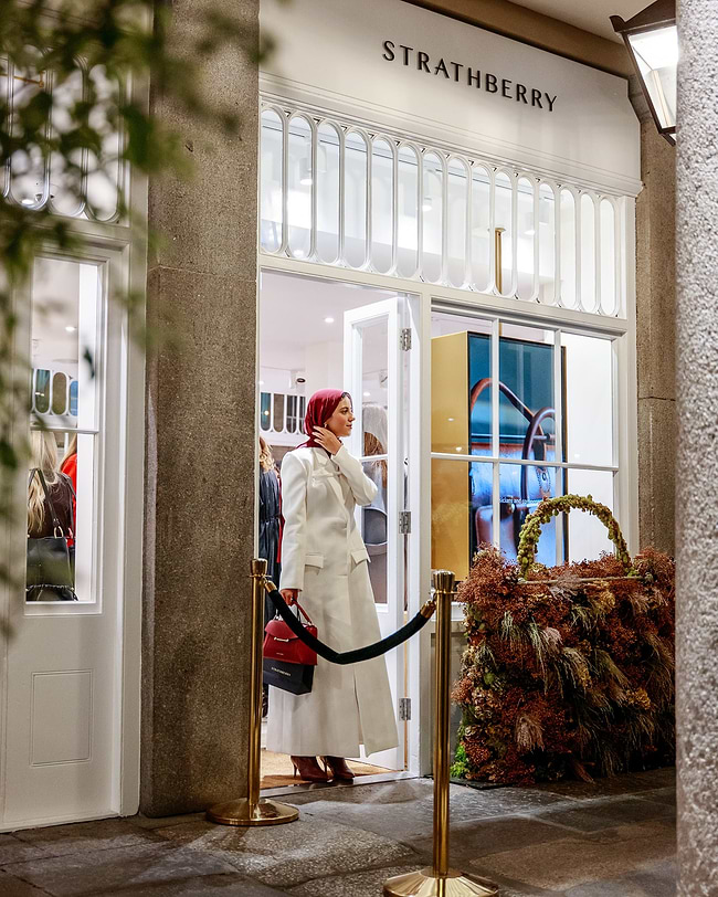 A woman in a white coat is standing outside of a store